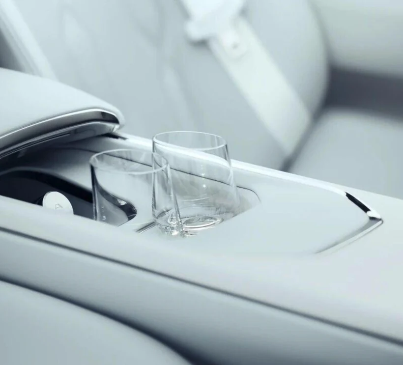 图片展示了BMW Vision Alpina Concept概念车的车内细节。画面中，车门内侧的杯架处放置着两个透明玻璃杯，杯架边缘有银色装饰。车门内侧为浅灰色，座椅为白色，座椅靠背部分有银色装饰条。